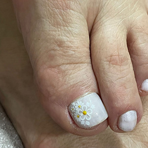 Pedicure com esmalte branco e detalhe floral