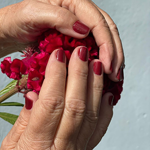 Unhas vermelhas em composição com flores