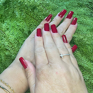 Manicure vermelha fotografada junto a plantas