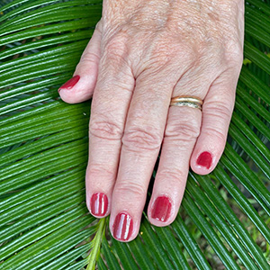 Manicure vermelha fotografada junto a folhagem